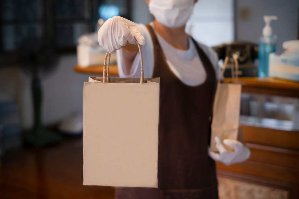Delivery man delivering grocery bag wearing face mask and gloves